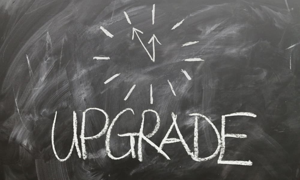 White chalk on a blackboard says upgrade, with a clock drawn above the words.